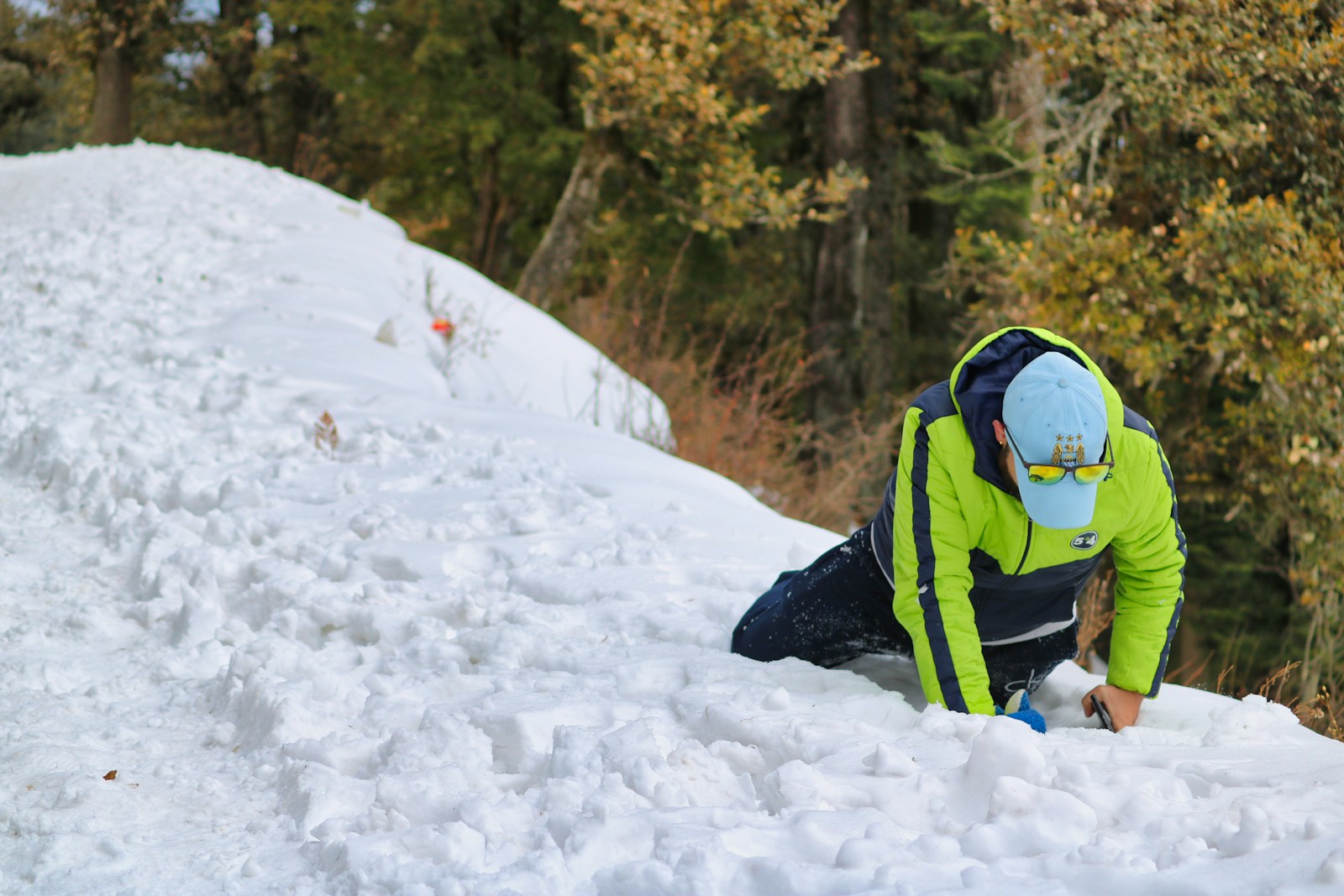 a man in a yellow jacket is digging in the snow
